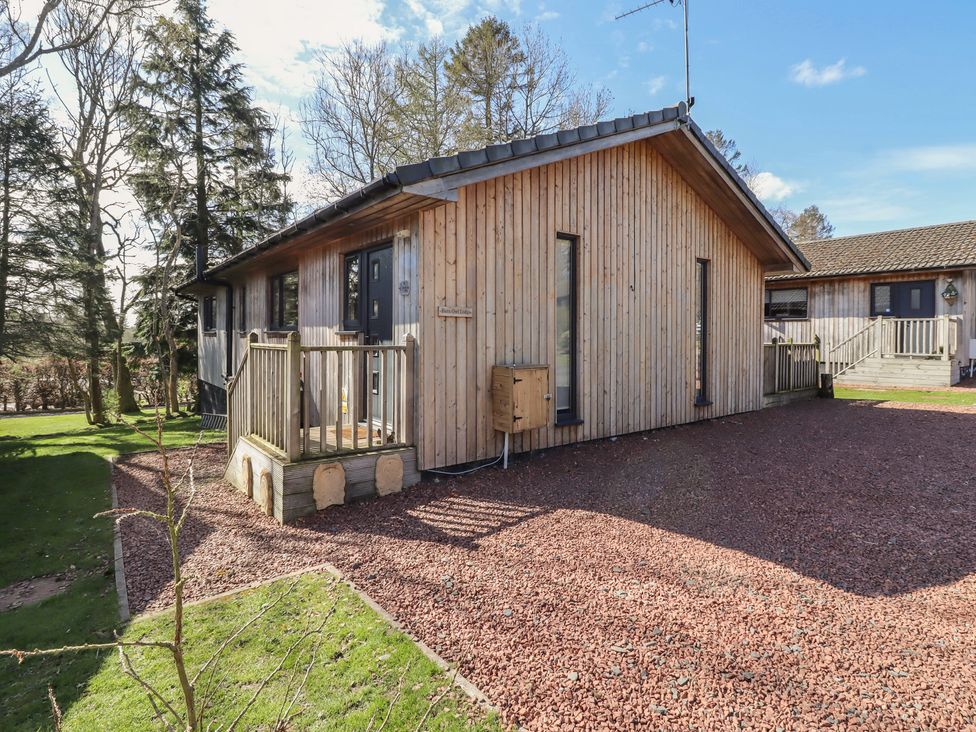 A wooden house with a garden and decking at Barn Owl in Otterburn
