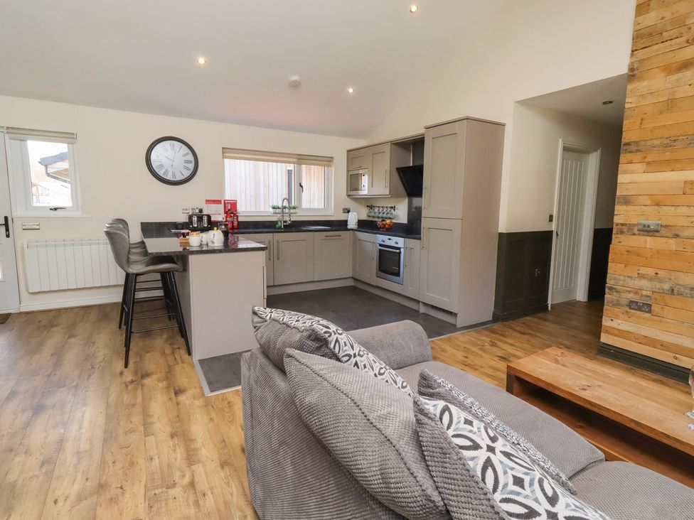 A kitchen with barstools and a sofa at Barn Owl in Otterburn