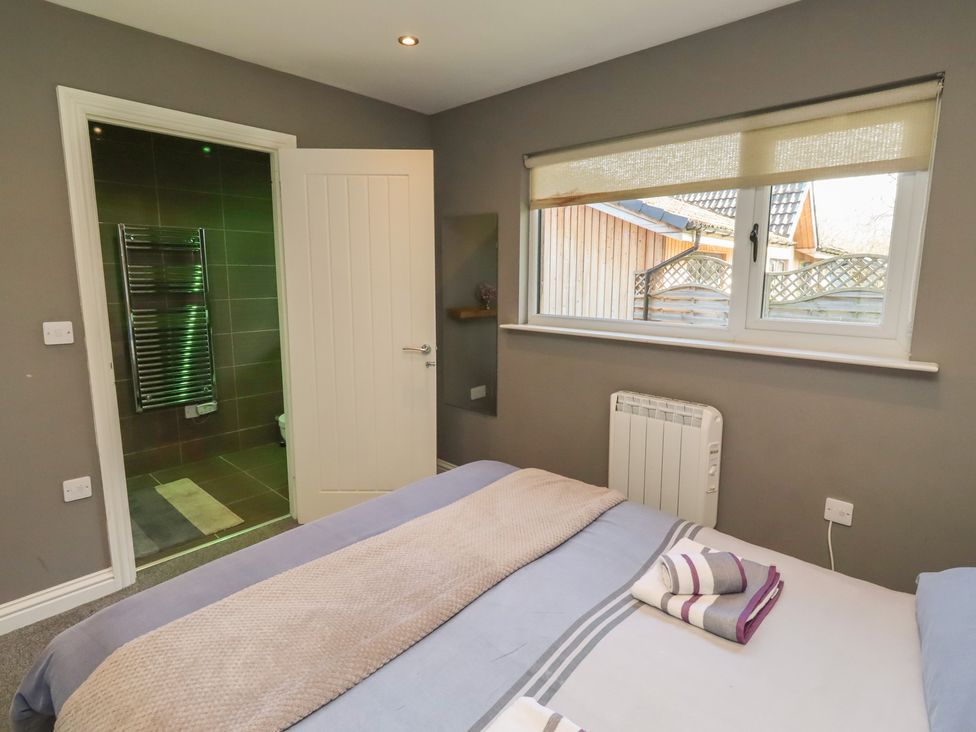 A bedroom with a bed and a bathroom door at Barn Owl in Otterburn