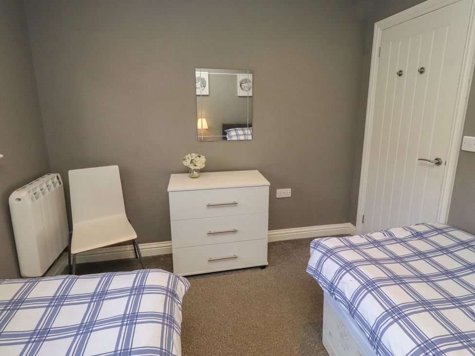 A bedroom with two beds and a dresser at Barn Owl in Otterburn