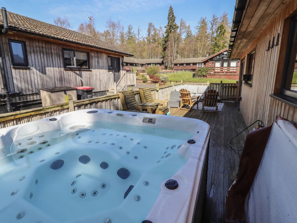 An outdoor area with a hot tub and wooden furniture at Barn Owl in Otterburn