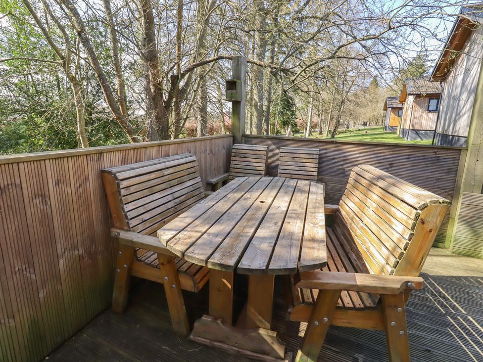 An outdoor seating area with wooden furniture at Barn Owl Otterburn