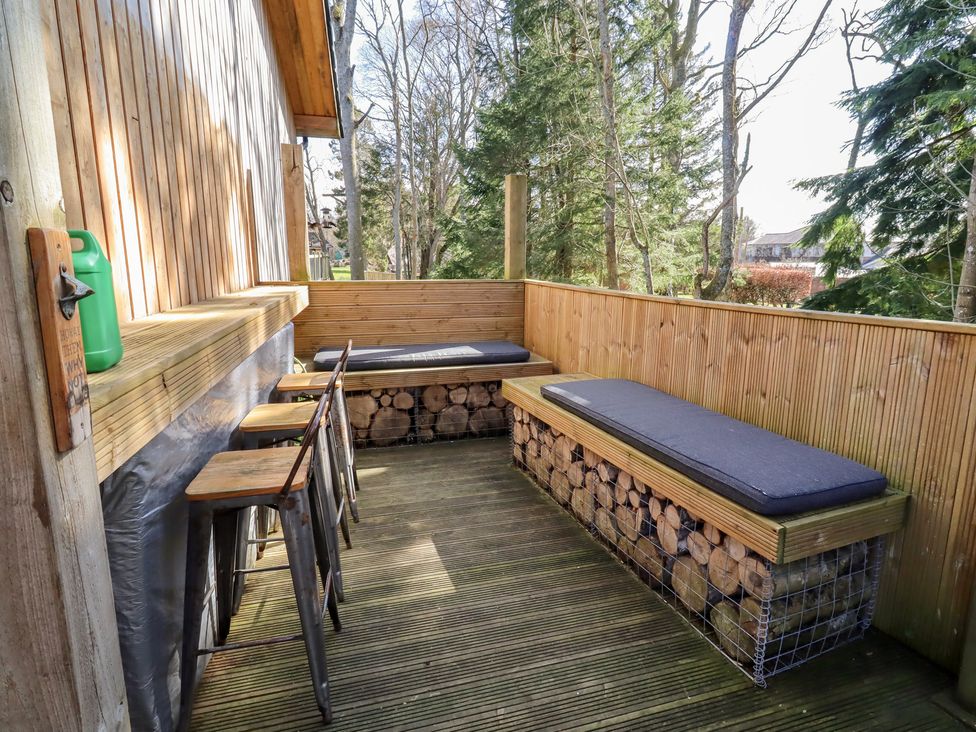 An outdoor seating area with wooden benches and green container at Barn Owl in Otterburn