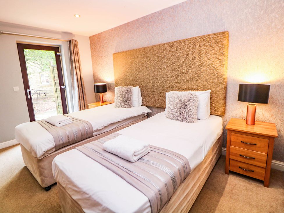 A bedroom with two beds and a door leading outside at Hassop in Matlock