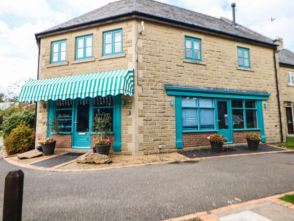 A building with a striped awning and planters at Hassop in Matlock