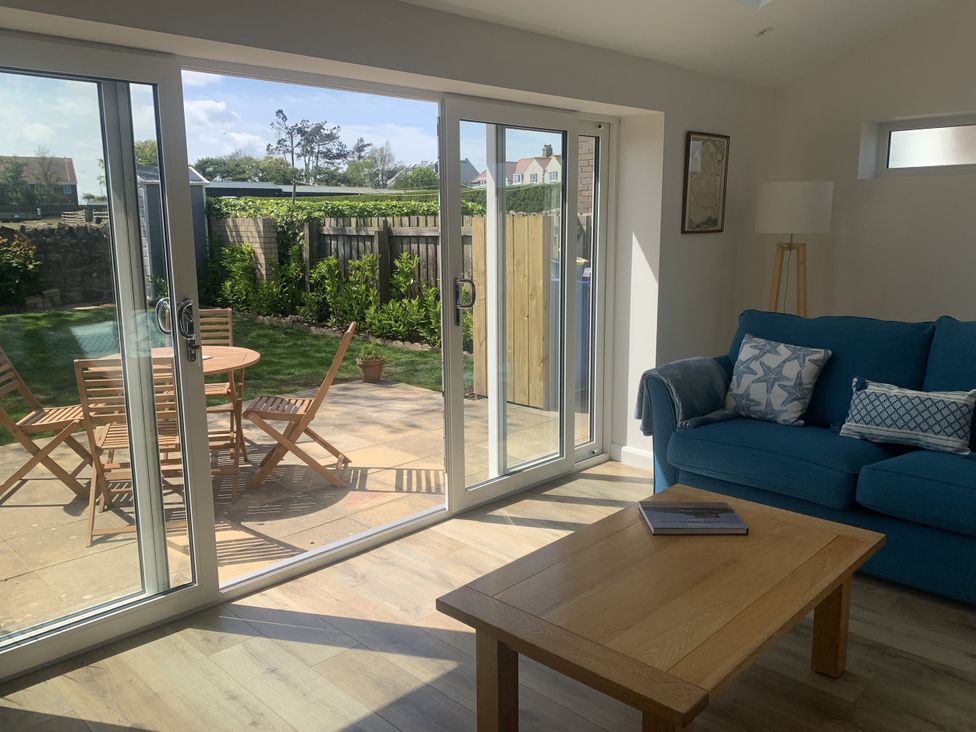 A living room with a glass door leading to a garden at The Nest in Beadnell