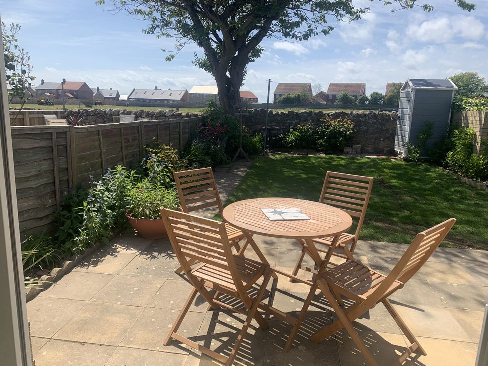 A garden with a table and chairs at The Nest in Beadnell