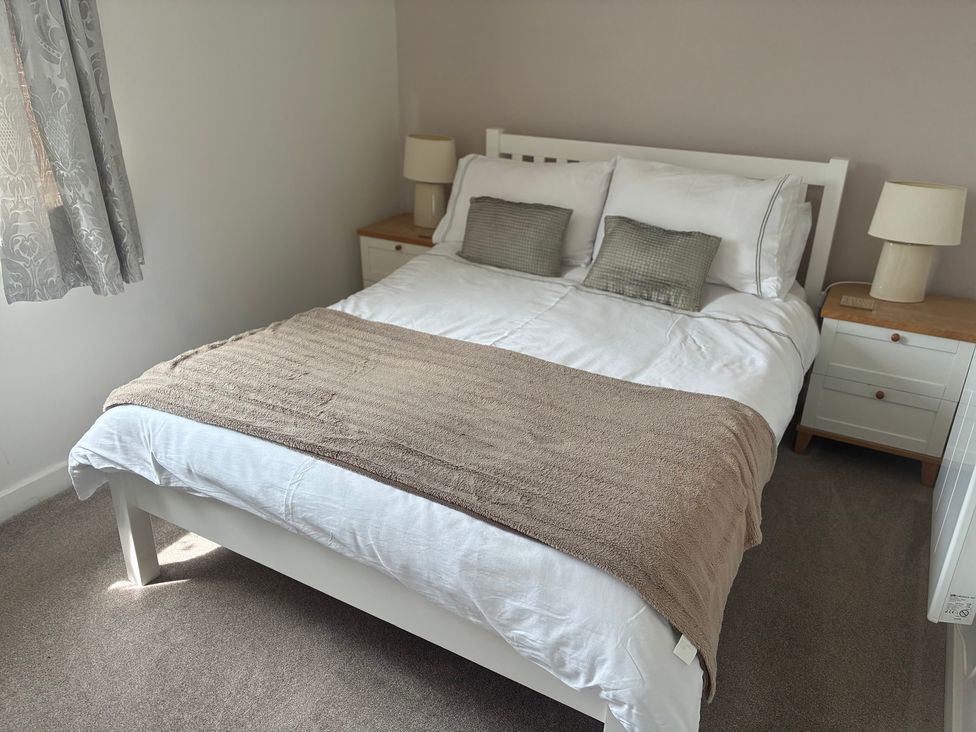 A bedroom with a bed and bedside tables at The Nest in Beadnell