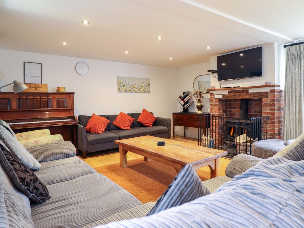 A living room with a piano, sofa, coffee table, and fireplace at Bwthyn Y Bugail (Shepherd's Cottage) Pedairffordd near Llanrhaeadr-Ym-Mochnant