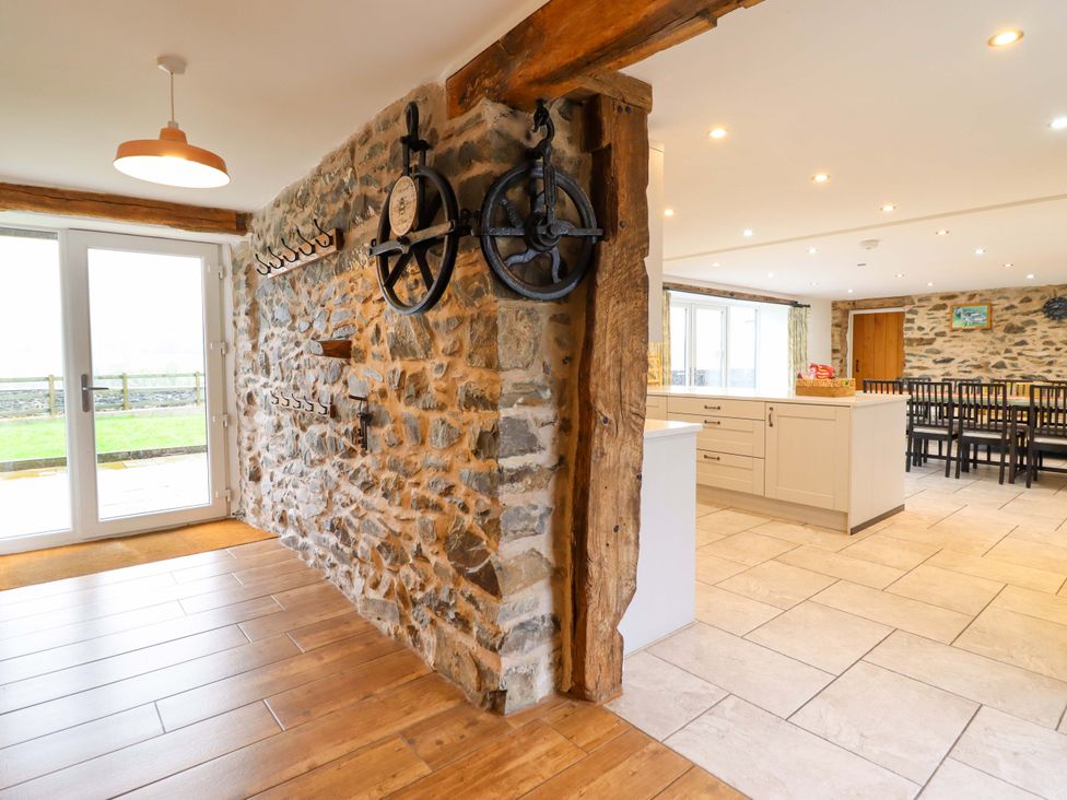 A kitchen with stone walls and dining area at Bwthyn Y Bugail (Shepherd's Cottage) Pedairffordd near Llanrhaeadr-Ym-Mochnant