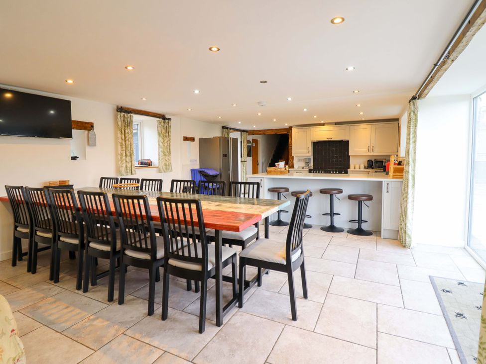 A kitchen with a large dining table and bar stools at Bwthyn Y Bugail (Shepherd's Cottage) Pedairffordd near Llanrhaeadr-Ym-Mochnant