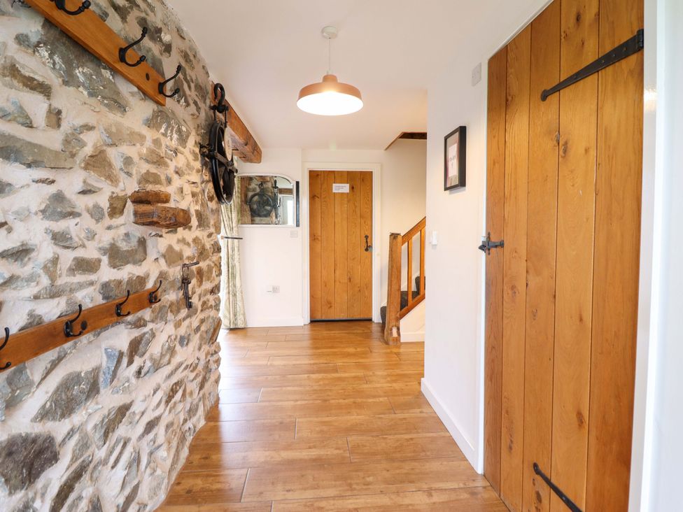 A hallway with a stone wall and wooden door at Bwthyn Y Bugail (Shepherd's Cottage) Pedairffordd near Llanrhaeadr-Ym-Mochnant