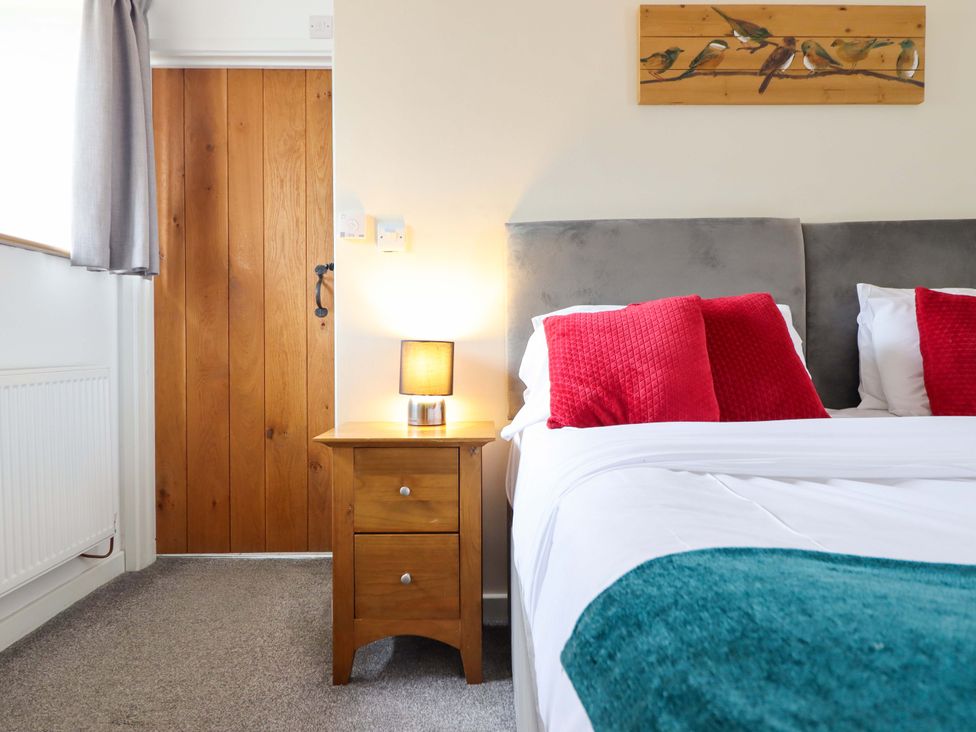 A bedroom with a bed and bedside table at Bwthyn Y Bugail (Shepherd's Cottage) Pedairffordd near Llanrhaeadr-Ym-Mochnant