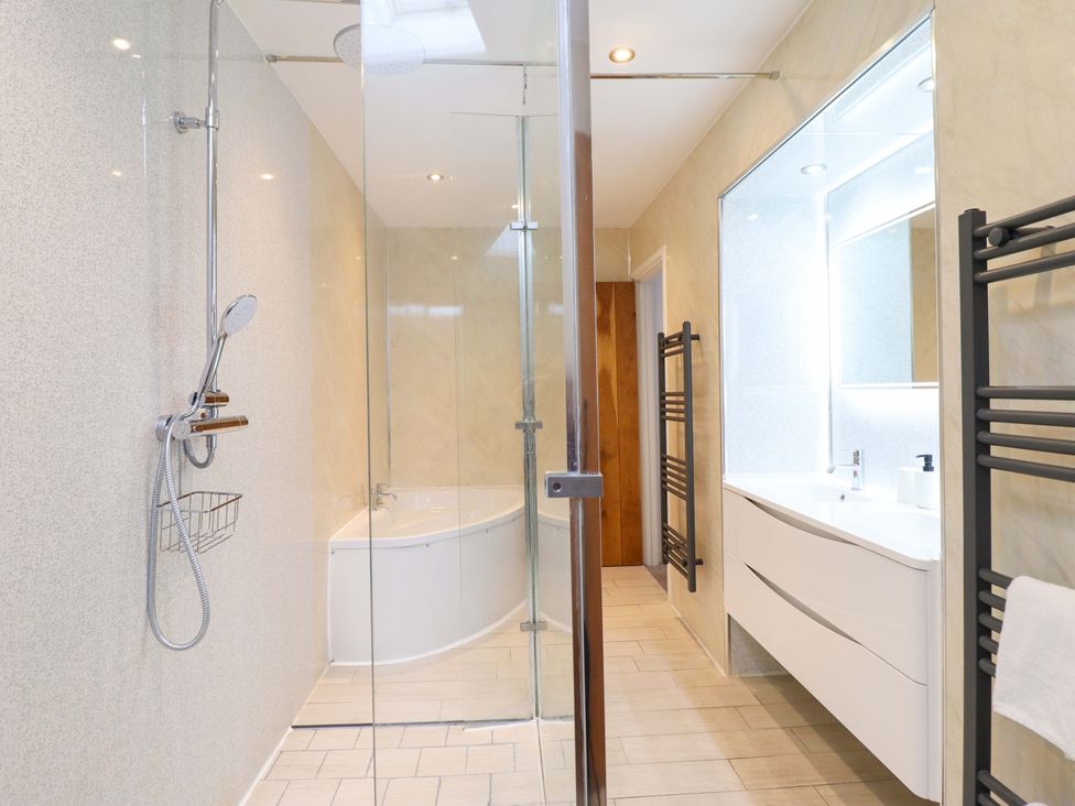 A bathroom featuring a shower, bathtub, and sink at Bwthyn Y Bugail (Shepherd's Cottage) Pedairffordd near Llanrhaeadr-Ym-Mochnant