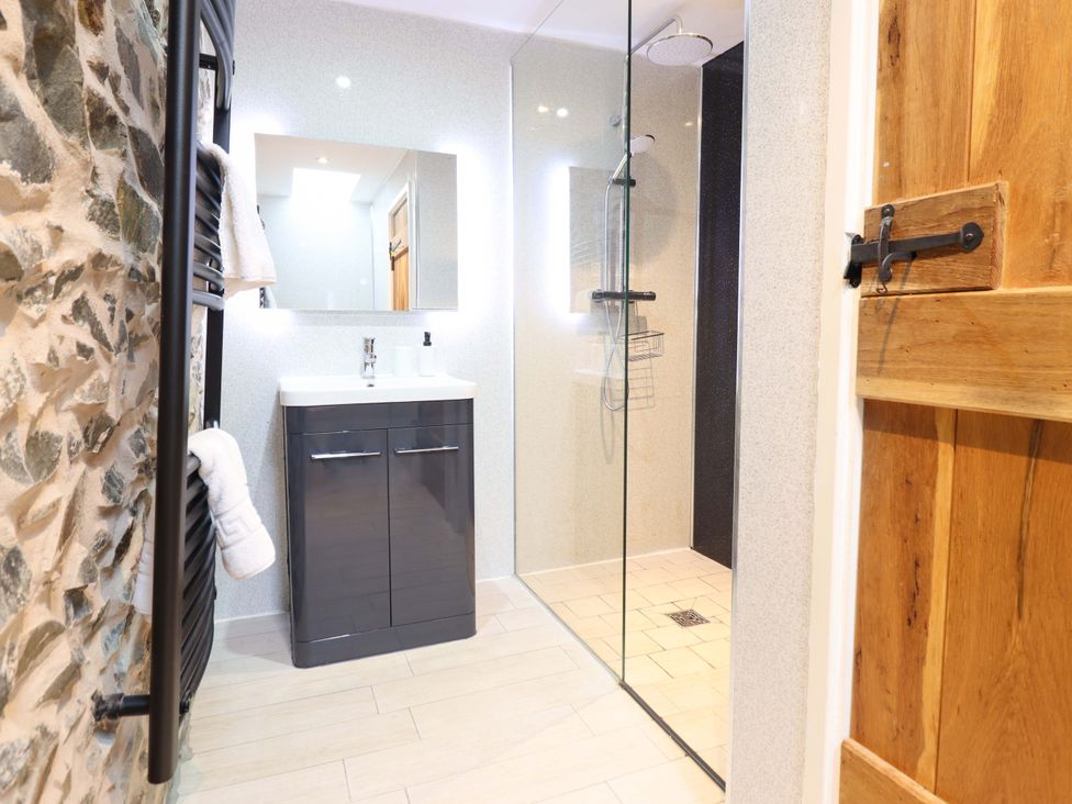 A bathroom with a shower and sink at Bwthyn Y Bugail (Shepherd's Cottage) Pedairffordd near Llanrhaeadr-Ym-Mochnant