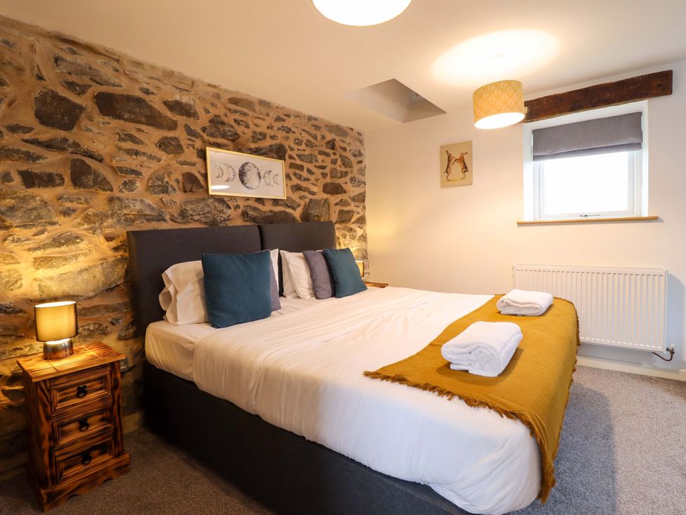 A bedroom with stone wall and bed at Bwthyn Y Bugail (Shepherd's Cottage) Pedairffordd near Llanrhaeadr-Ym-Mochnant