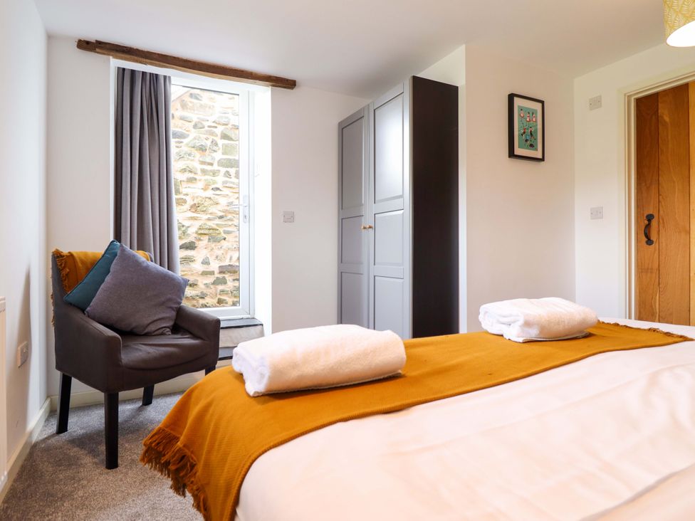 A bedroom with a bed, towels on top, and a chair at Bwthyn Y Bugail (Shepherd's Cottage) Pedairffordd near Llanrhaeadr-Ym-Mochnant