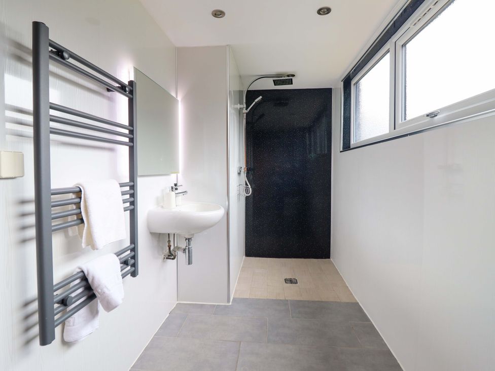 A bathroom with a towel radiator and sink at Bwthyn Y Bugail (Shepherd's Cottage) near Pedairffordd near Llanrhaeadr-Ym-Mochnant