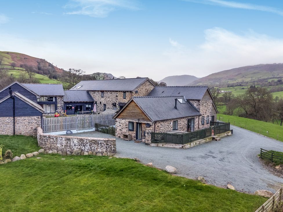 An exterior view of a house with a fence and driveway at Y Beudy (The Dairy) Pedairffordd near Llanrhaeadr-Ym-Mochnant