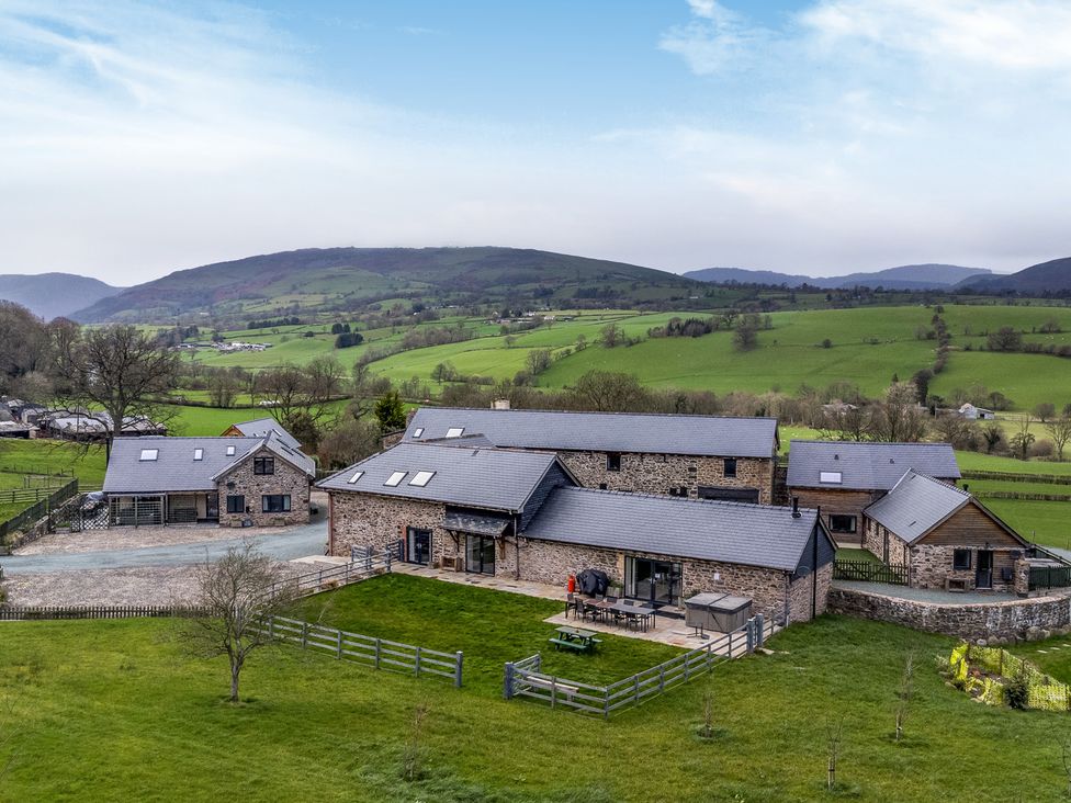 An outdoor area with stone buildings and furniture at Y Granar (The Granary) Llanrhaeadr-Ym-Mochnant