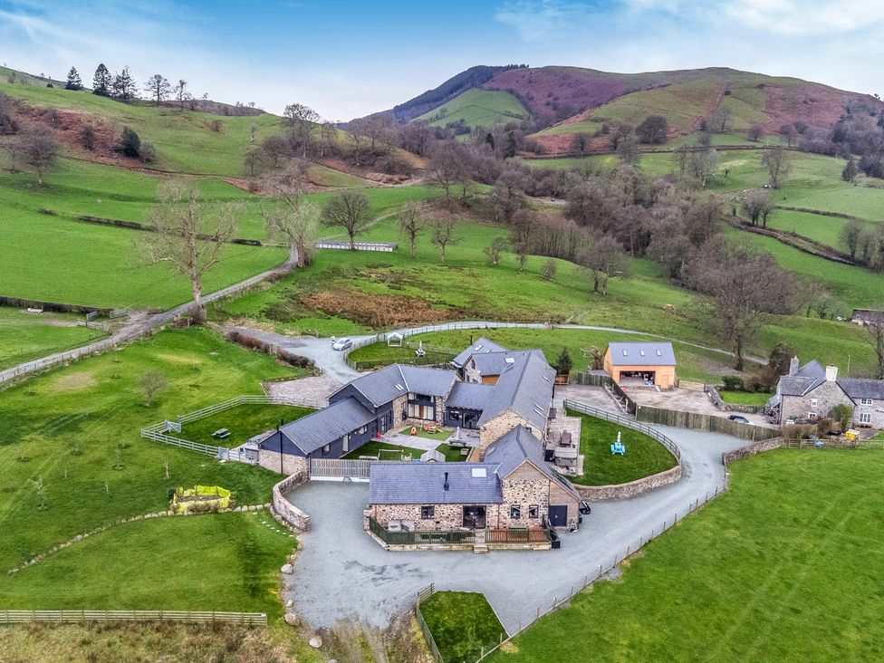 An aerial view of houses surrounded by fields and mountains at Y Granar (The Granary) Llanrhaeadr-Ym-Mochnant