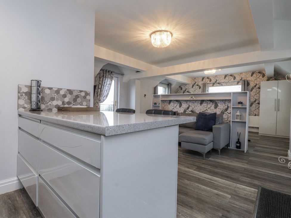 A kitchen with a countertop and bar stools at The Wren in Llysfaen