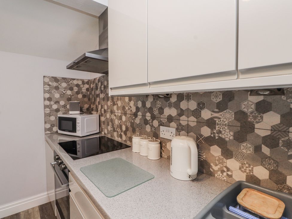 A kitchen with a microwave and electric stove at The Wren in Llysfaen