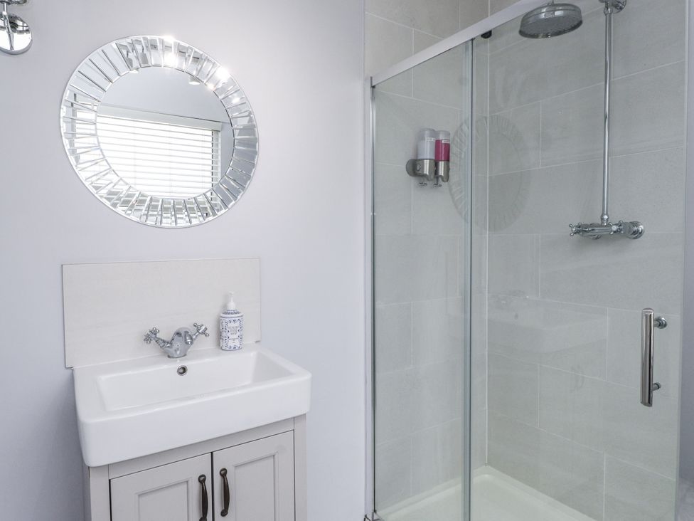 A bathroom with a shower and washbasin at The Wren in Llysfaen