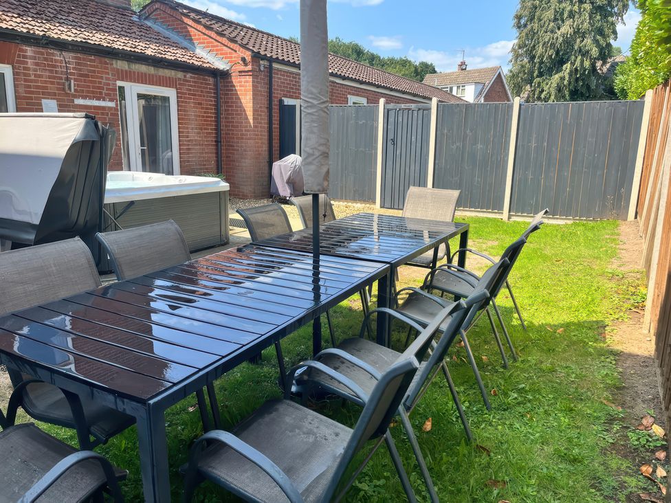 A garden with a table and chairs near a hot tub at Sunnymeade in Buxton, Norfolk