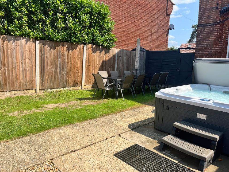 A garden with a hot tub and a dining area at Sunnymeade in Buxton, Norfolk