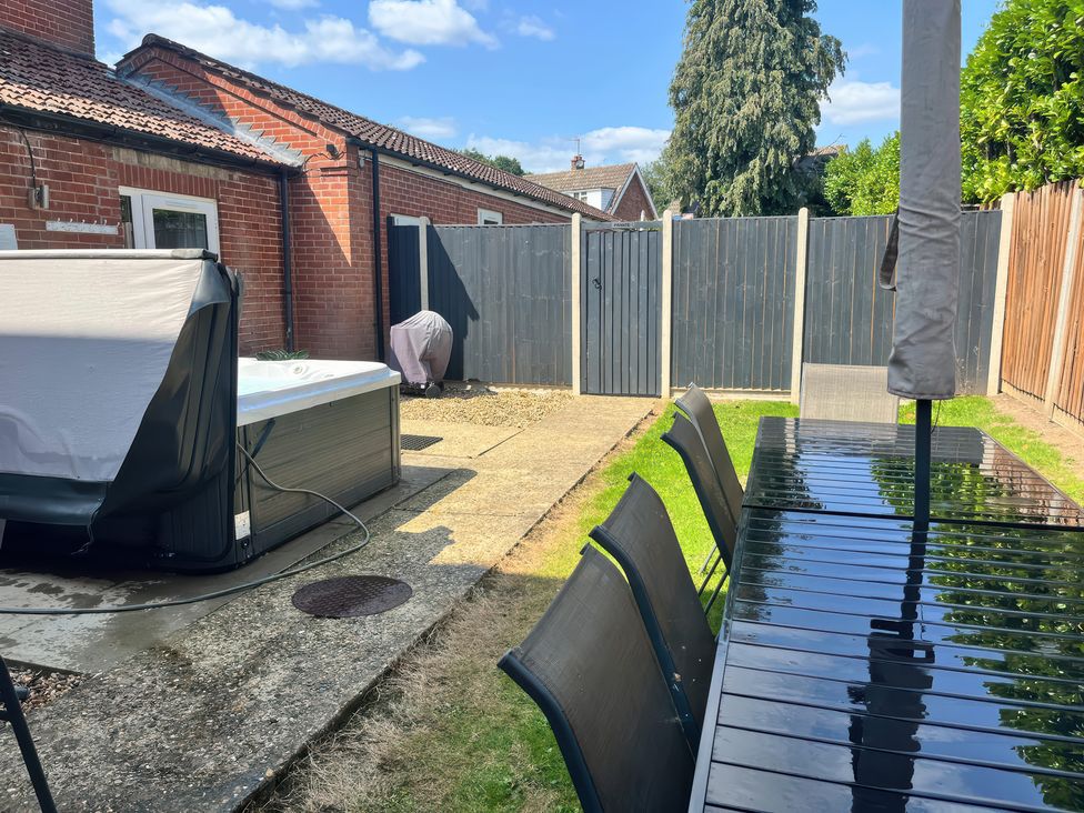 A garden with a hot tub, table and chairs at Sunnymeade, Buxton, Norfolk