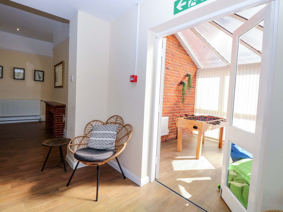 A sitting room with a chair and a foosball table at Sunnymeade in Buxton, Norfolk