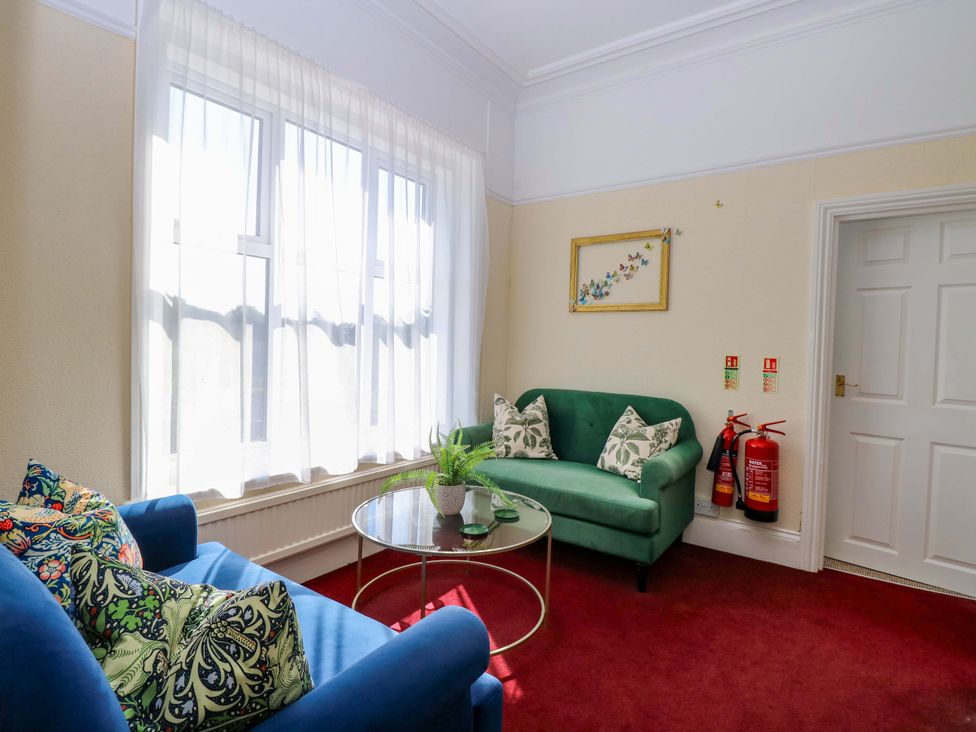 A snug with a green sofa, blue sofa, coffee table and plant at Sunnymeade Buxton, Norfolk
