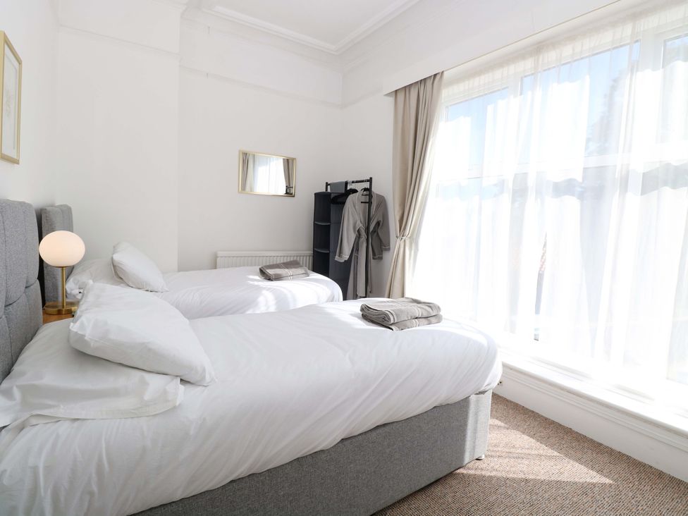 A bedroom with two beds, a lamp, and a clothes rack at Sunnymeade in Buxton, Norfolk