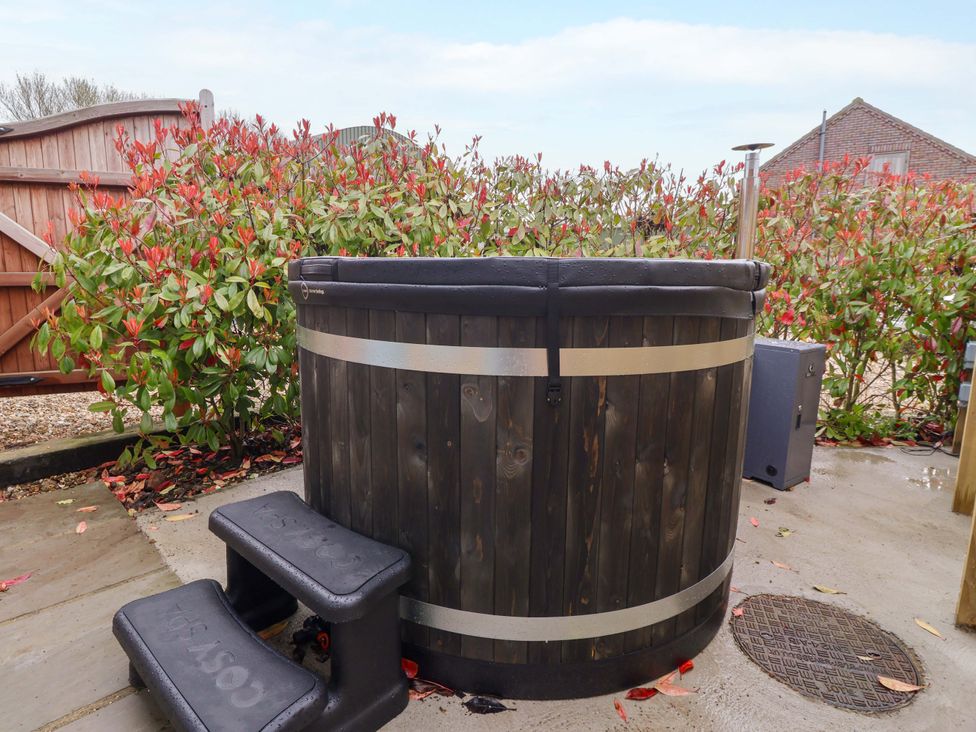 A hot tub with steps and plants in the garden at Plough Cottage Little Kelk near Bridlington