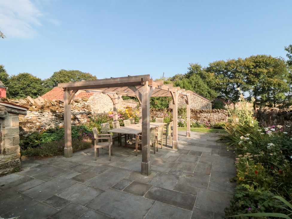 A garden with a table and chairs under a pergola at Bute Cottage in Lockton near Pickering