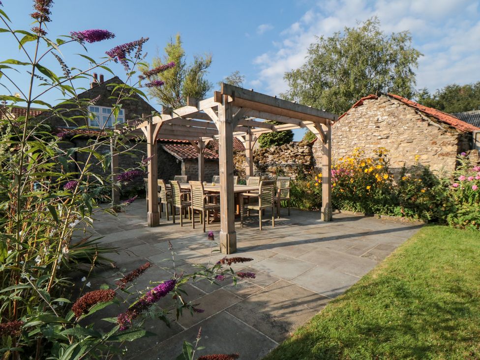 A garden with a dining area under a pergola at Bute Cottage in Lockton near Pickering