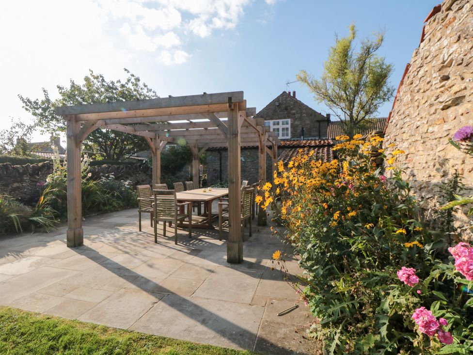 A garden with a pergola and outdoor dining set at Bute Cottage Lockton near Pickering