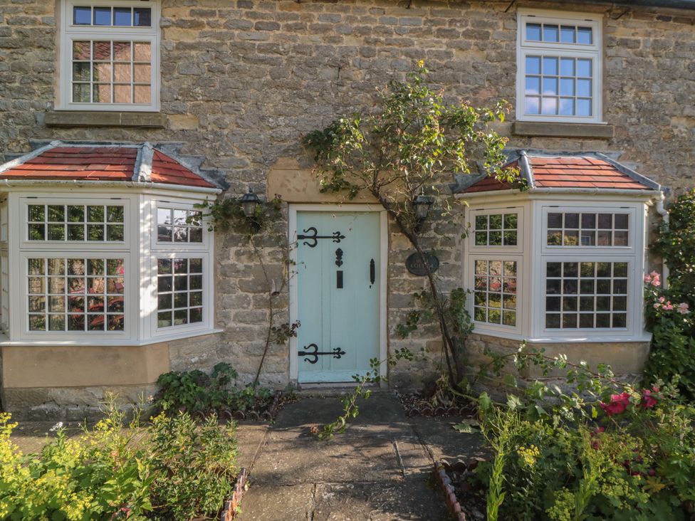 A stone cottage facade with green door and windows at Bute Cottage Lockton near Pickering