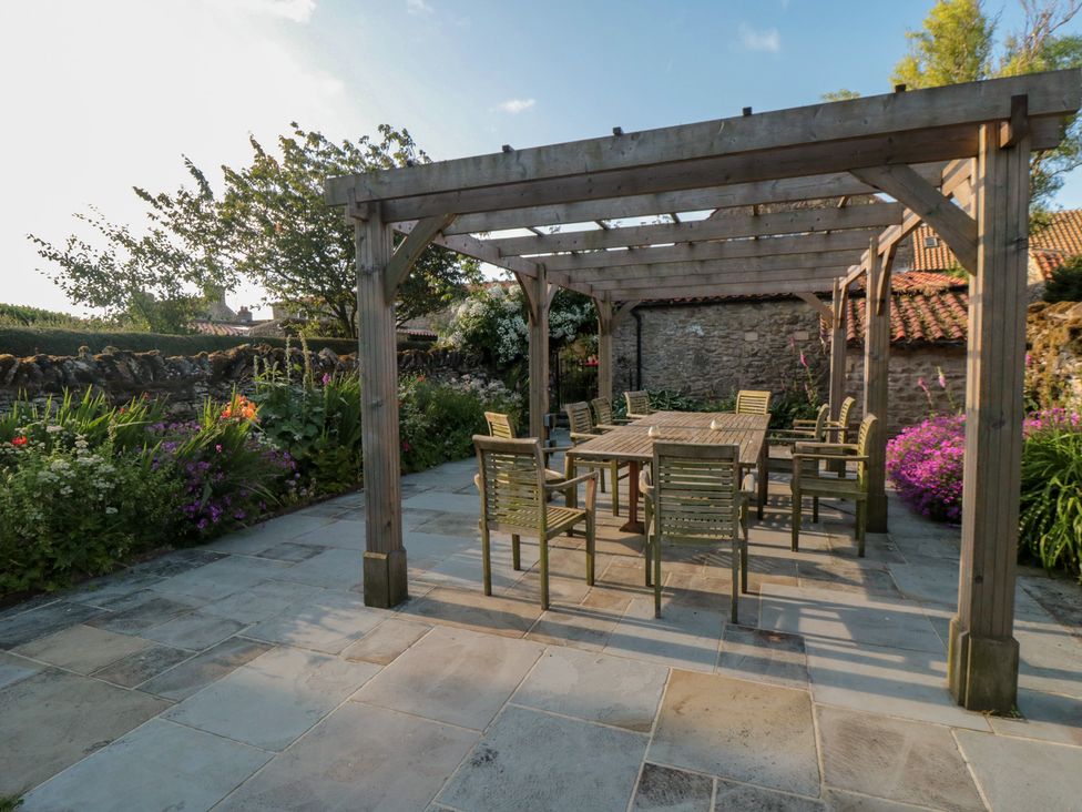 A garden with a wooden pergola and dining set at Bute Cottage in Lockton near Pickering