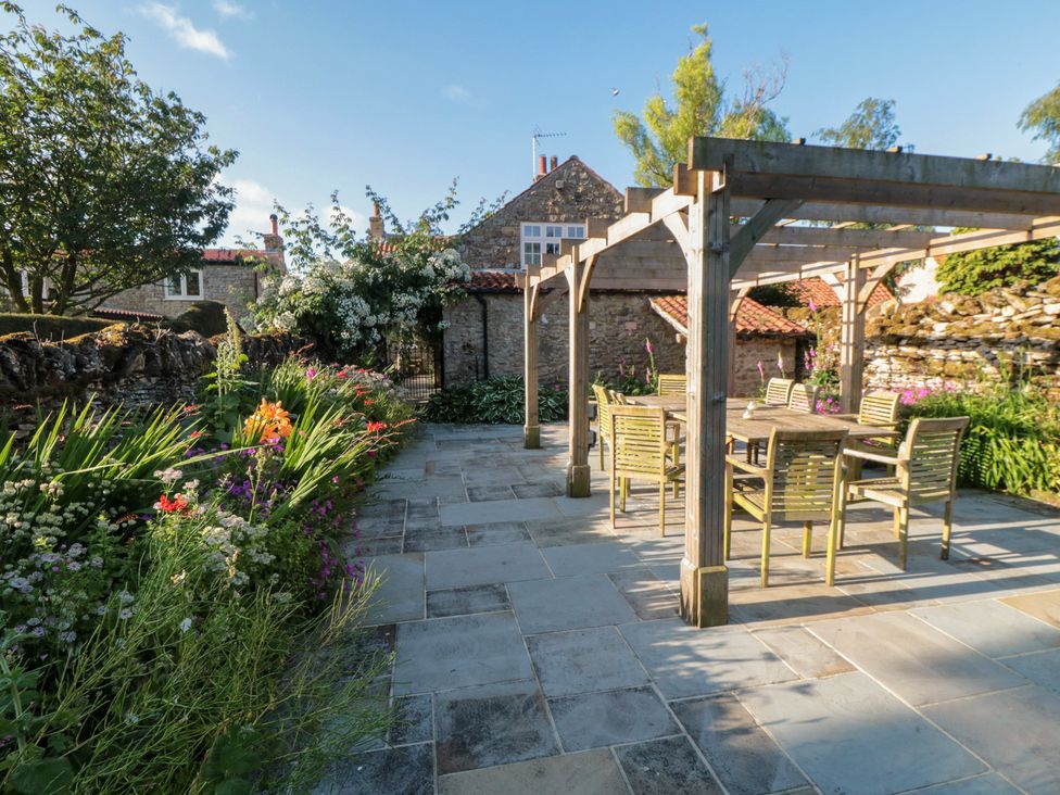 A garden with a stone patio and seating area at Bute Cottage Lockton near Pickering