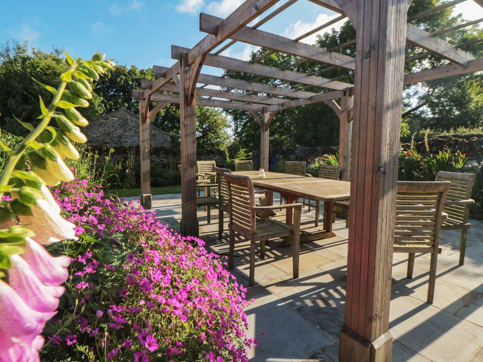 A garden with a wooden pergola and dining set at Bute Cottage Lockton near Pickering