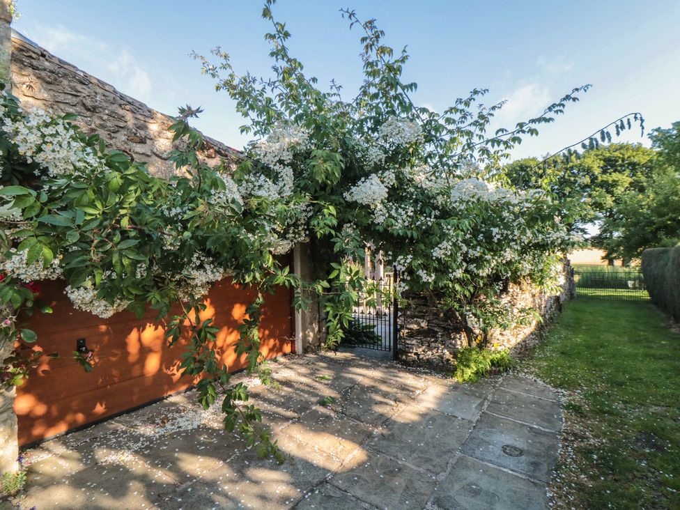 A garage with a gate and flowering plants in front at Bute Cottage Lockton near Pickering