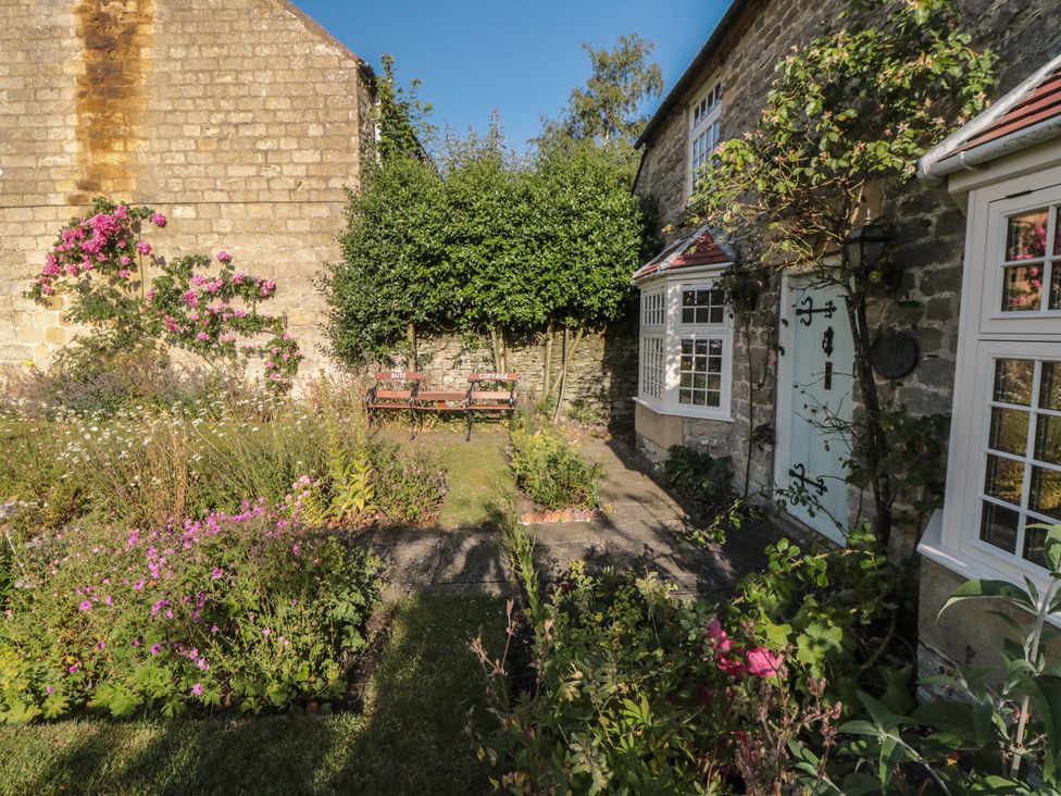 A garden with flowers and a bench at Bute Cottage Lockton near Pickering