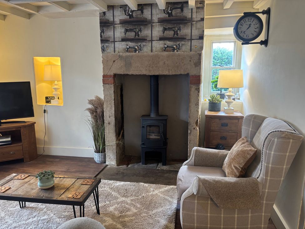 A living room with a fireplace and television at Coupling Cottage in Belper