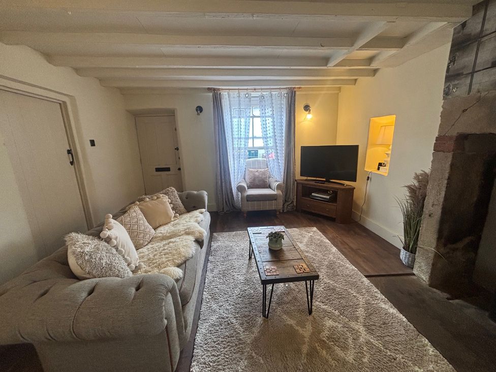 A living room with a sofa and a television at Coupling Cottage in Belper