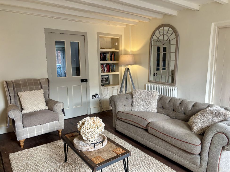 A living room with an armchair, sofa, and coffee table at Coupling Cottage in Belper