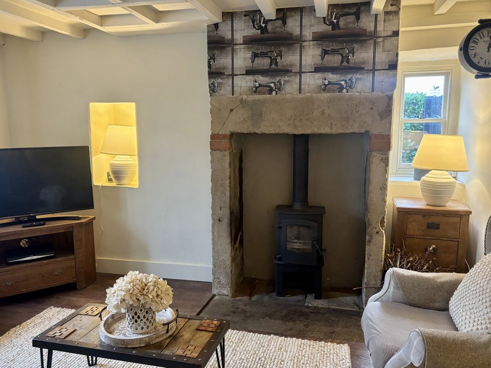 A living room with a stove and television at Coupling Cottage in Belper