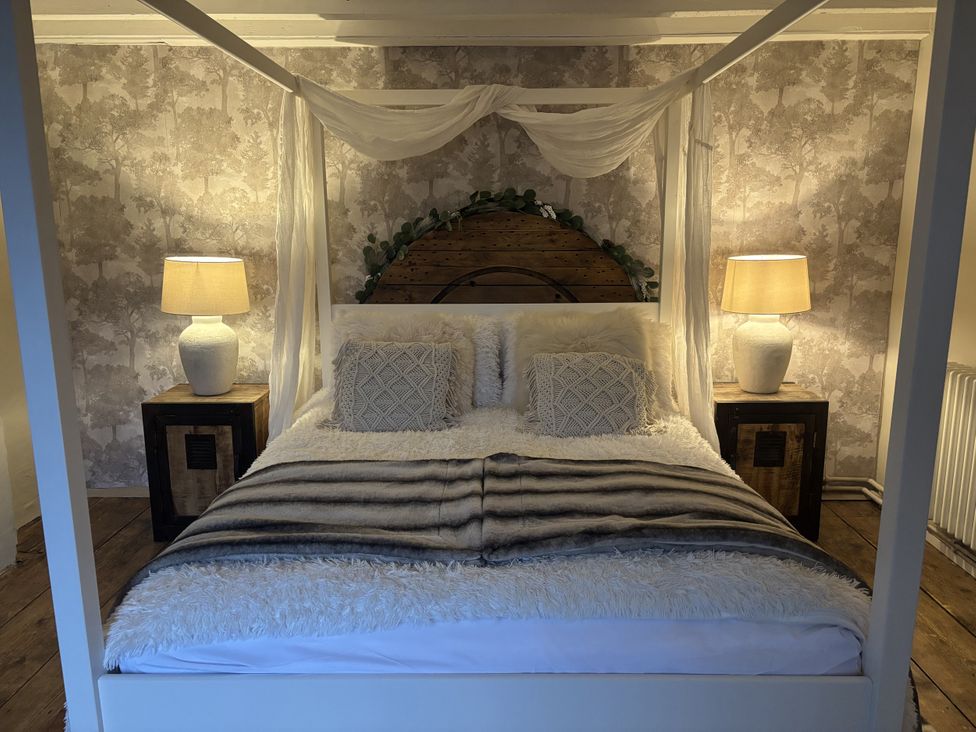 A bedroom featuring a four-poster bed with a blanket at Coupling Cottage in Belper