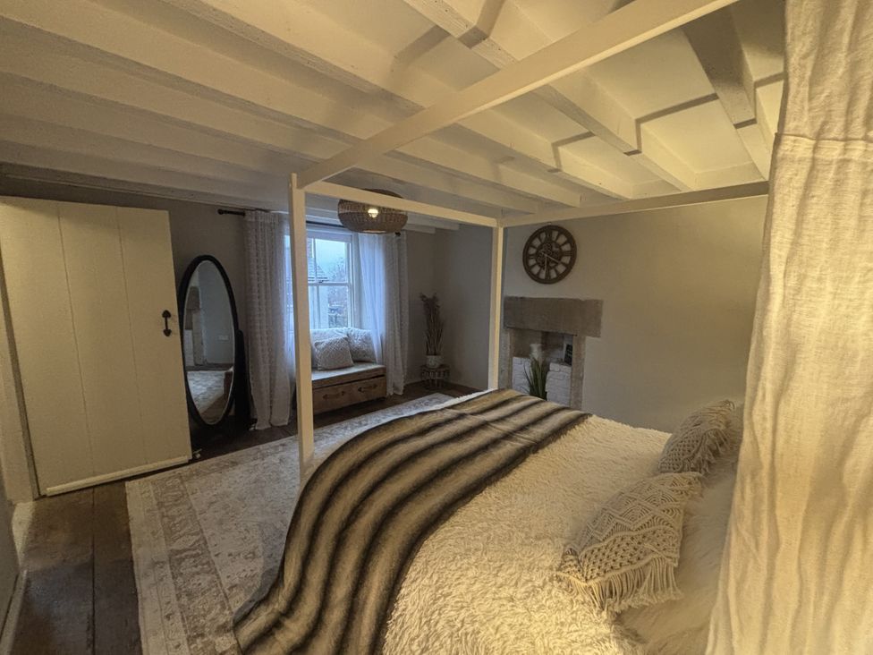 A bedroom with a bed and mirror at Coupling Cottage Belper